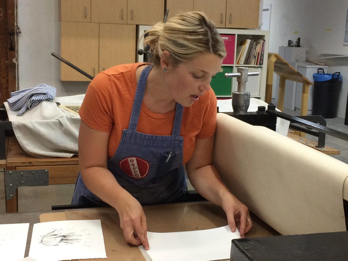 Woman in orange shirt preparing to make a print in Myrtle Press