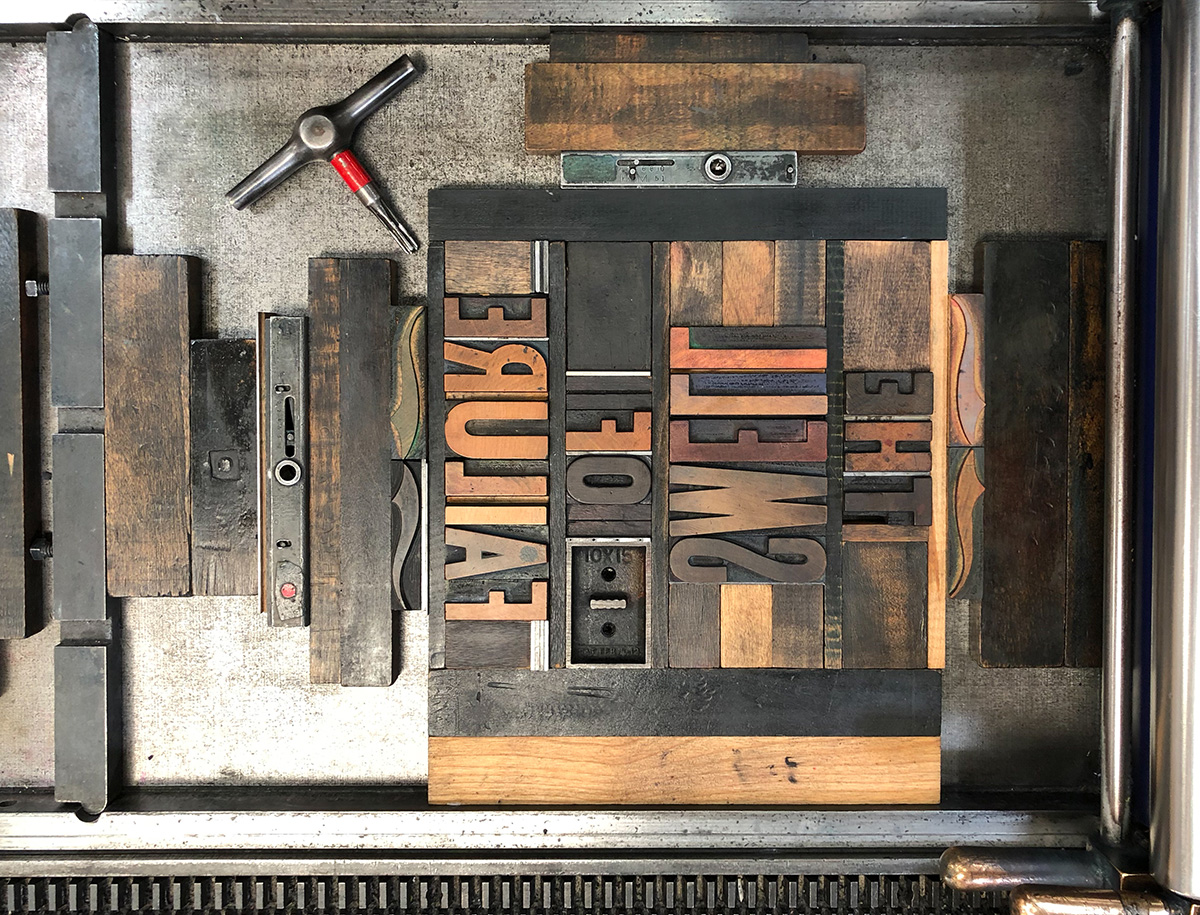 Printing press letters arranged on a press spelling out "the smell of failure" backwards