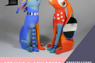 two dog like sculptures. One is blue with a orange red leg. One is red orange with a blue leg.